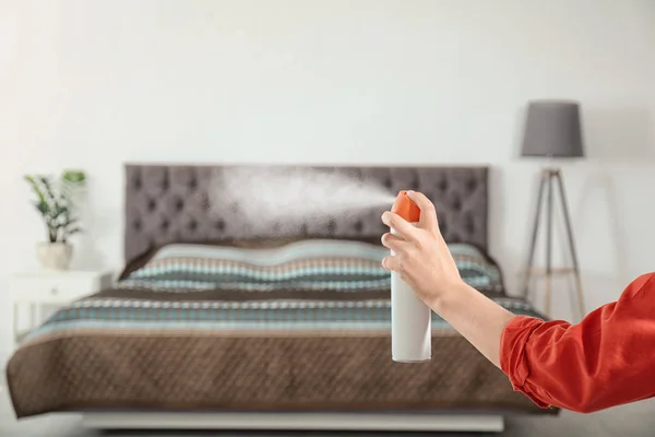 Woman spraying air freshener in bedroom