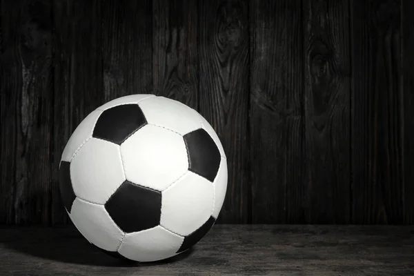 New soccer ball on table against wooden background. Football equipment