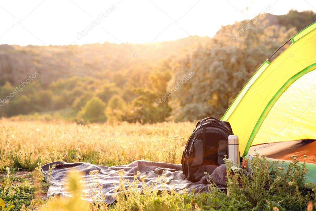 Camping gear and tourist tent in wilderness on sunny day