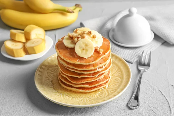 Stack of tasty pancakes with banana, nuts and honey on table