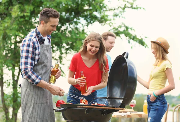 Young people having barbecue with modern grill outdoors