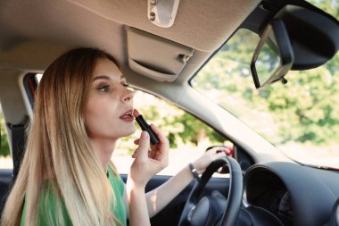 Güzel dikkatsiz kadın arabada makyaj uygulamak