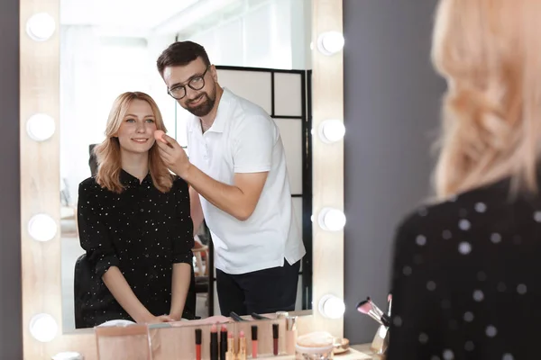 Professional makeup artist working with client in dressing room