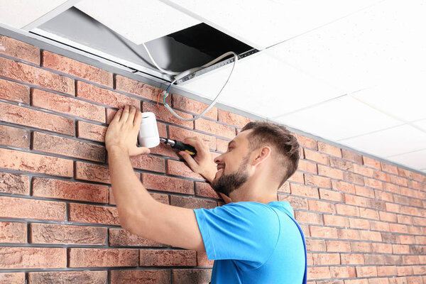 Male technician installing alarm system indoors