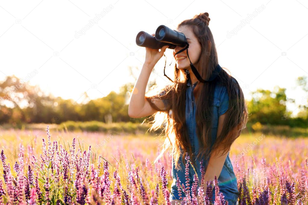 Teenage girl with binoculars in field. Summer camp