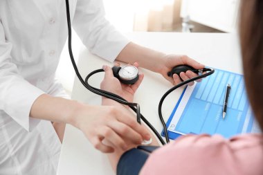 Kadın doktor Kliniği içinde kilolu kadın kan basıncı ölçme