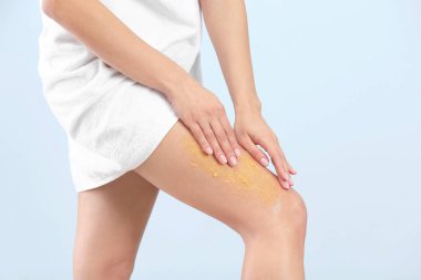 Genç kadın bacak açık renkli karşı vücut scrub uygulayarak