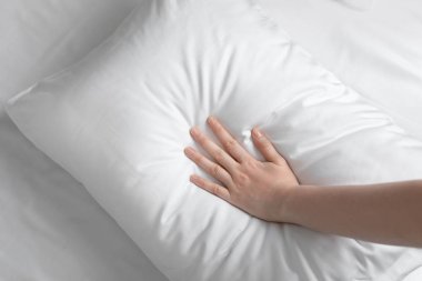 Young woman touching soft white pillow, closeup clipart