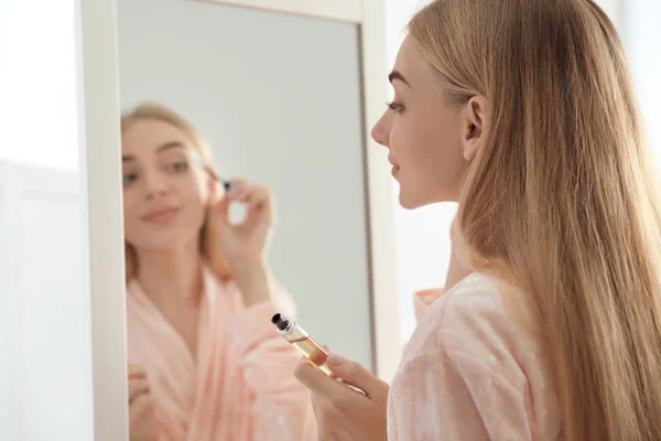 年轻妇女涂抹油在她的睫毛附近镜子室内 — 图库照片