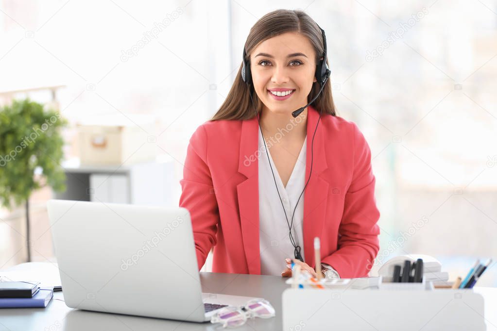 Young woman talking on phone through headset at workplace