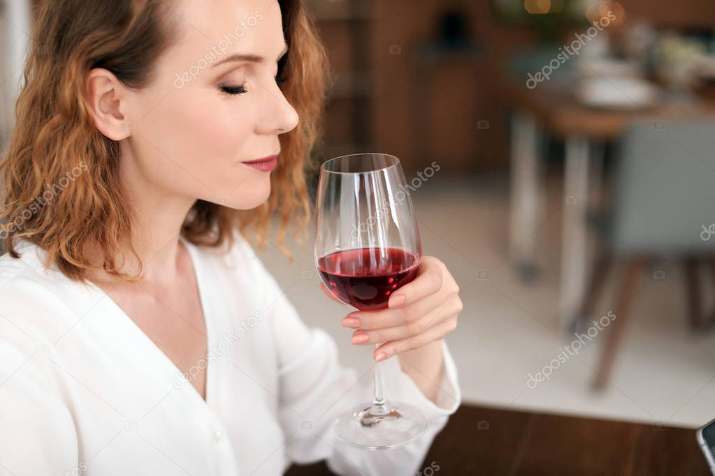 Woman with glass of delicious wine indoors