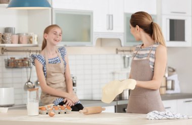 Anne ve kızı mutfakta masada hamur yapma