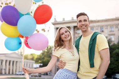 Genç çift renkli balonlarla açık havada güneşli günde