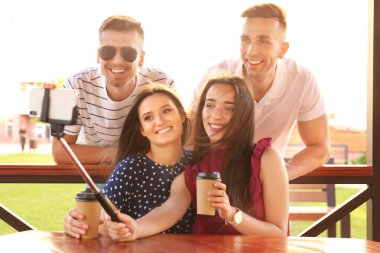 Bir grup genç insan monopod ile selfie çardak içinde güneşli günde alarak.