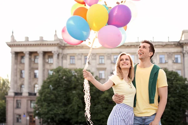 阳光明媚的日子 年轻的情侣带着五颜六色的气球在户外 — 图库照片
