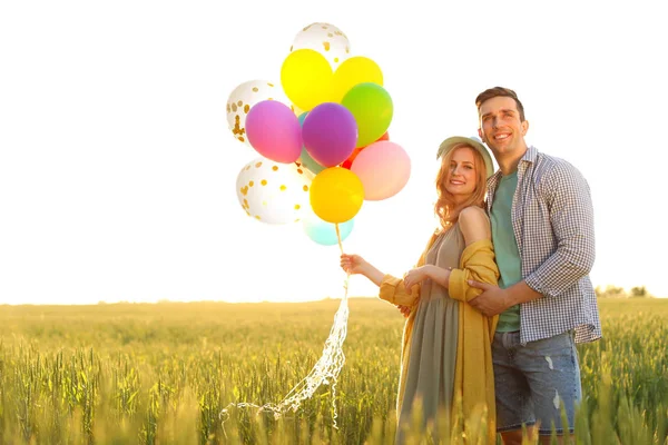 阳光明媚的日子 年轻的情侣带着五颜六色的气球在户外 — 图库照片