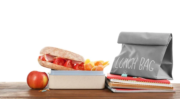 Lunch box with appetizing food and bag on table against white background