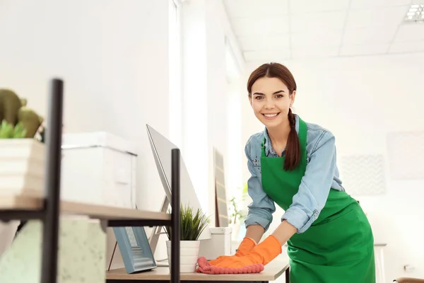 Young woman in apron and gloves cleaning office