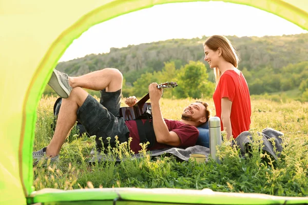 Young couple spending time together in wilderness, view from inside of camping tent