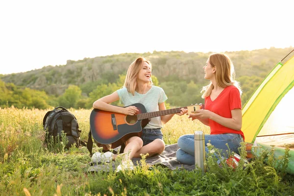 Mujeres Jóvenes Descansando Con Bebida Caliente Guitarra Cerca Tienda Campaña —  Fotos de Stock