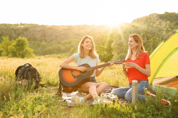 Mujeres Jóvenes Descansando Con Bebida Caliente Guitarra Cerca Tienda Campaña —  Fotos de Stock