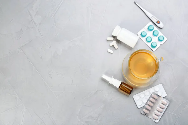 Cup with hot tea, pills and drugs for cold on table, top view