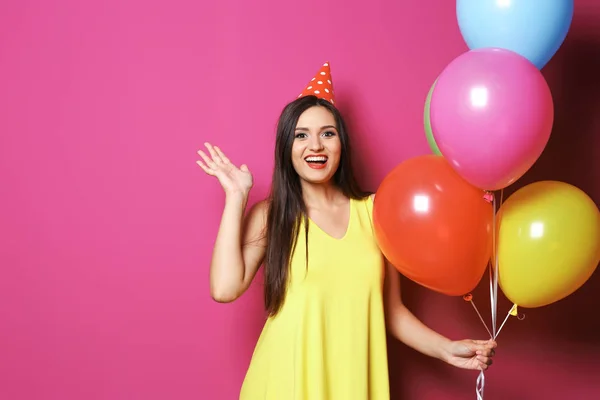 色の背景に明るい風船を持つ若い女性 誕生日のお祝い — ストック写真