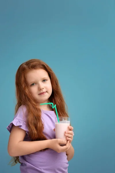 おいしいミルクセーキ色の背景上のガラスを持つ少女 — ストック写真