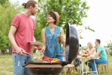 Young people having barbecue with modern grill outdoors clipart