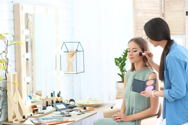 Profesyonel visage sanatçı salonda kadının yüzünde makyaj uygulamak