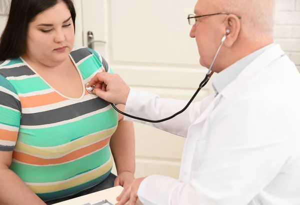 Doctor listening to patient\'s heartbeat with stethoscope in clinic