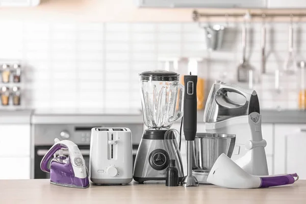 Household and kitchen appliances on table against blurred