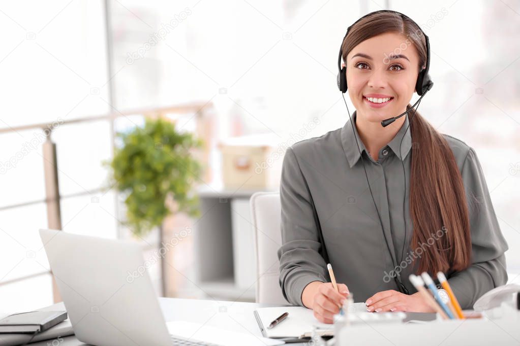 Young woman talking on phone through headset at workplace