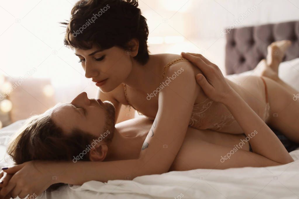 Lovely young couple being intimate on bed at home