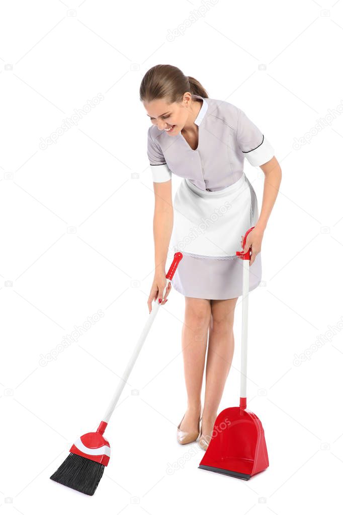 Young chambermaid with broom and dustpan on white background