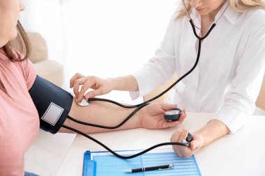Kadın doktor Kliniği içinde kilolu kadın kan basıncı ölçme
