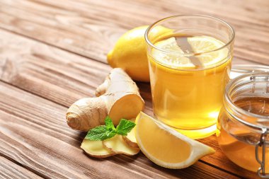 Sıcak çay, limon ve ahşap masa üzerinde soğuk ilaçlar olarak zencefil ile cam