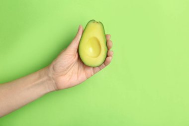 Olgun tutan kadın avokado renkli arka plan üzerinde kesmek.