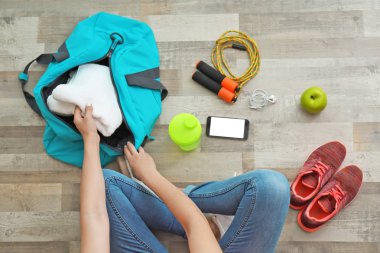 Genç kadın spor çanta ambalaj katta, üstten görünüm