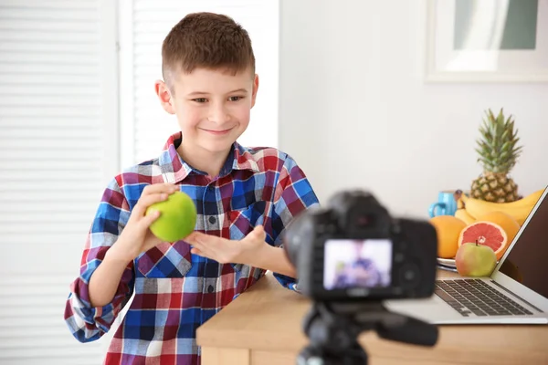 Cute little blogger with apple recording video at home