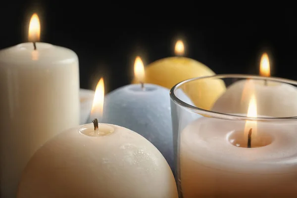 Burning wax candles of different shapes and colors, closeup