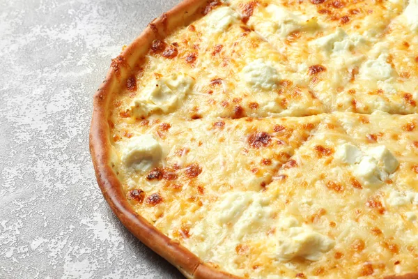 Gri zemin üzerine lezzetli sıcak peynirli pizza