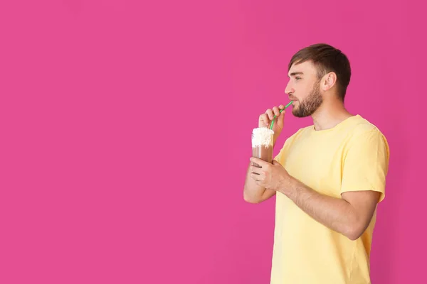 年轻男子与玻璃的美味奶昔的颜色背景 — 图库照片