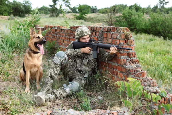 Man in military uniform with German shepherd dog at firing range