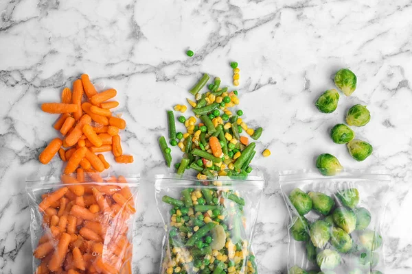 Πλαστικές Σακούλες Διάφορα Κατεψυγμένα Λαχανικά Μαρμάρινο Τραπέζι Top View — Φωτογραφία Αρχείου
