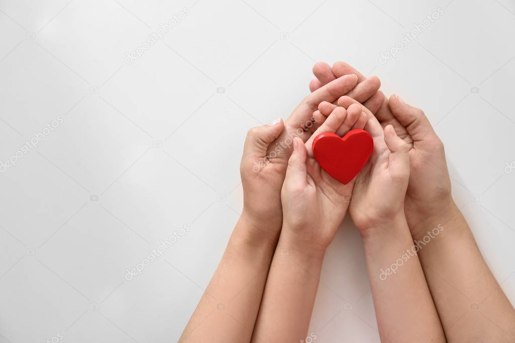 Young woman and child holding red heart on light background, top view