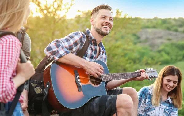 Sırt çantası için arkadaşları wilderness içinde gitar çalmak olan genç adam. Kamp sezon