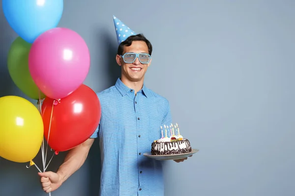 Jonge Man Met Verjaardagstaart Heldere Ballonnen Kleur Achtergrond — Stockfoto