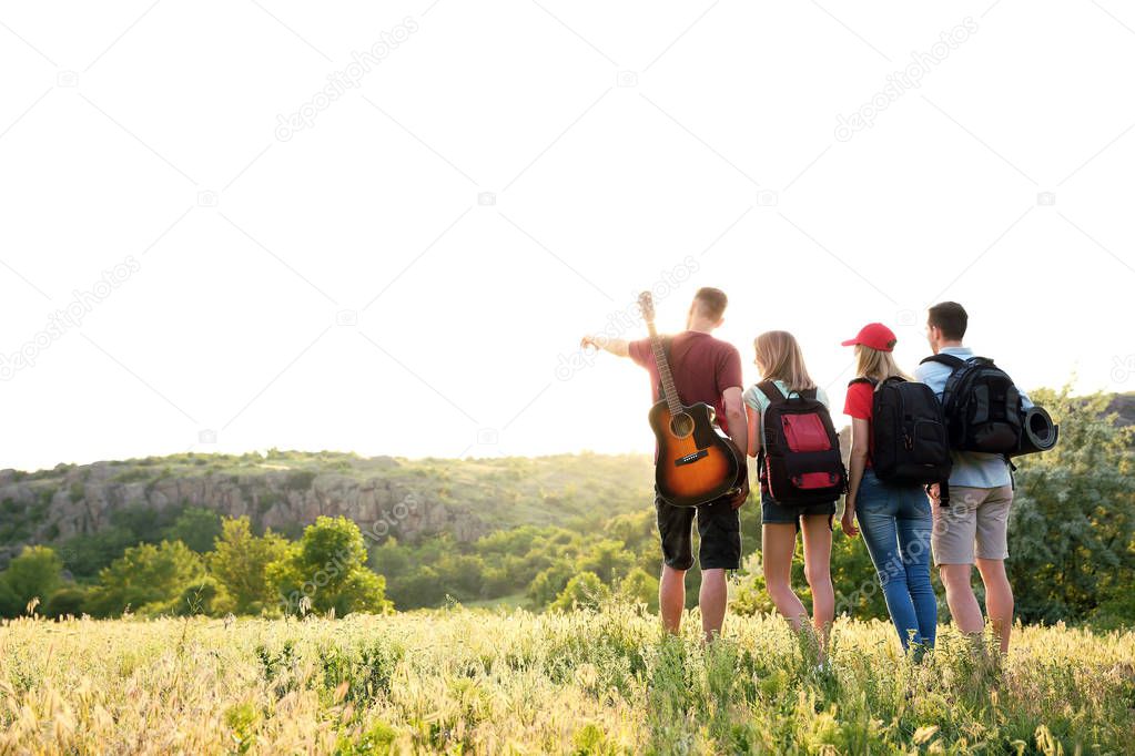 Group of young people with backpacks in wilderness. Camping season