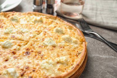 Gri masada leziz sıcak peynirli pizza.